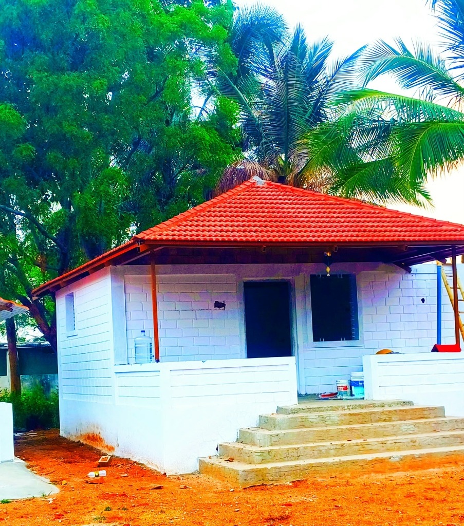 Eco-friendly farmhouse cottage built with interlocking mud blocks and traditional red clay roof tiles